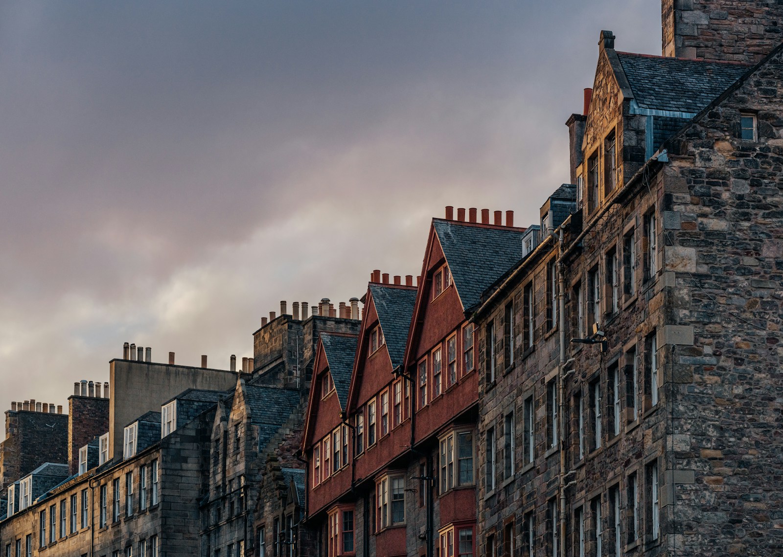 Row of old stone buildings under a cloudy sky